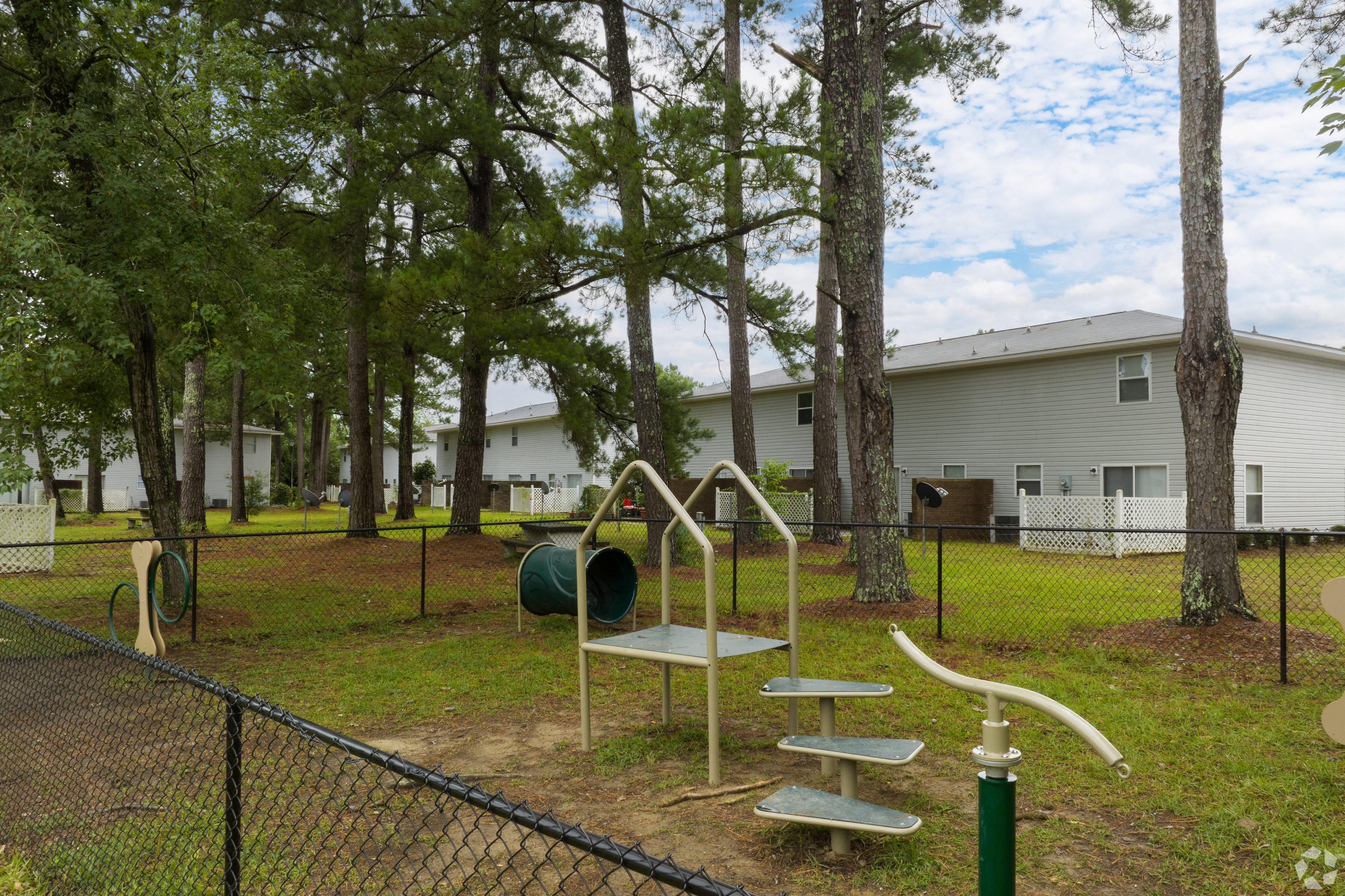 a playground in a park with trees and houses in the background
